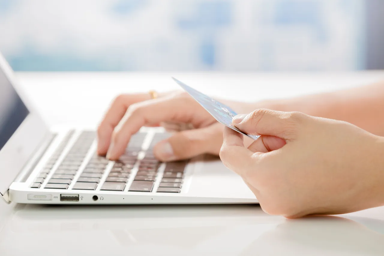 
A person making an online purchase using a credit card on a laptop, highlighting the convenience of digital transactions.